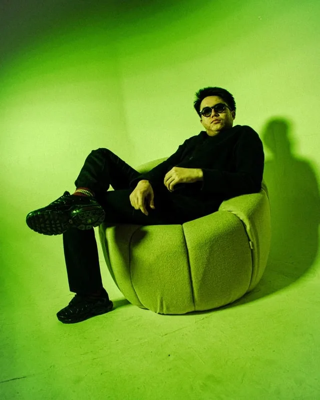Spinral DJ sitting on a lime green chair in a neon green studio